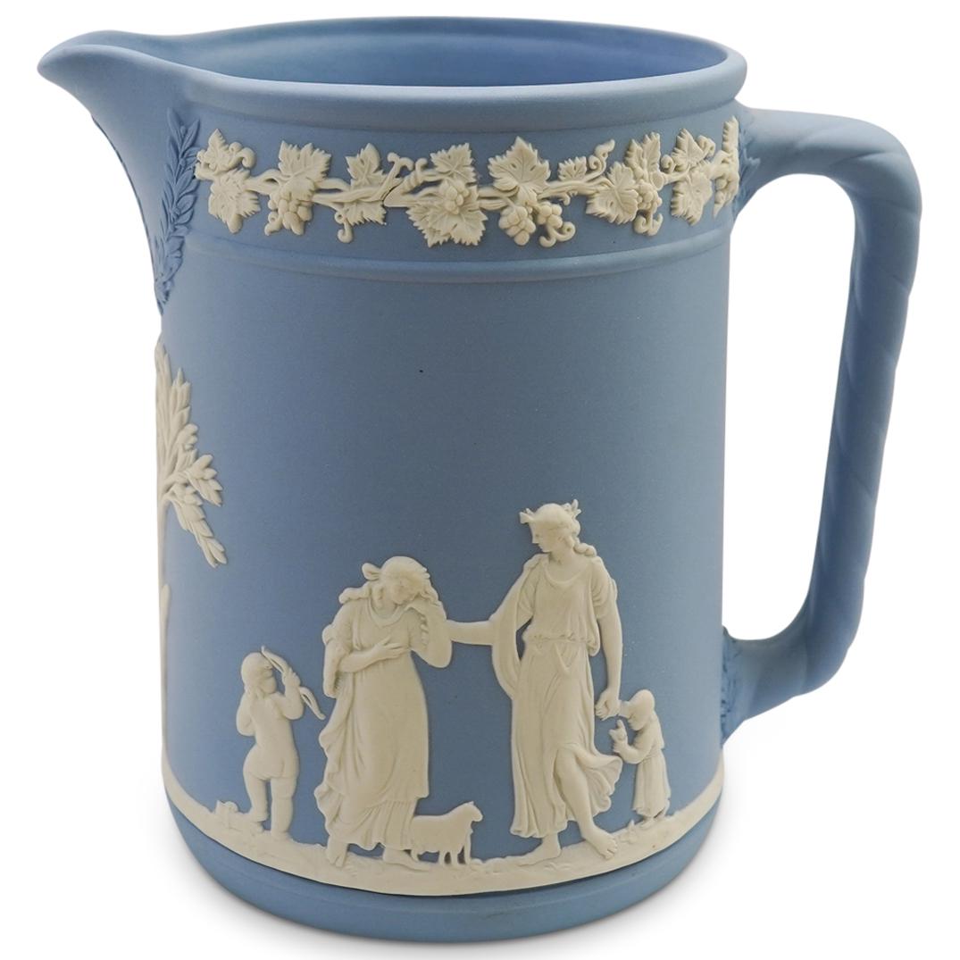 Wedgewood Jasper Porcelain Pitcher: DESCRIPTION: A Wedgewood porcelain pitcher features in a celestial biscuit foundation decorated along the body with Greco Roman figures, stamped along the bottom "Wedgewood Made In England".CIRCA: Ear