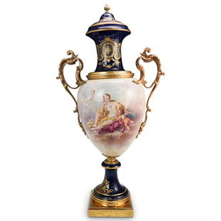 Large Sevres Porcelain and Bronze Urn: DESCRIPTION: A large antique Sevres urn composed of porcelain in classic Cobalt blue hues, hand painted along the front with scenes of a Maiden with putti angels, and architectural structures along