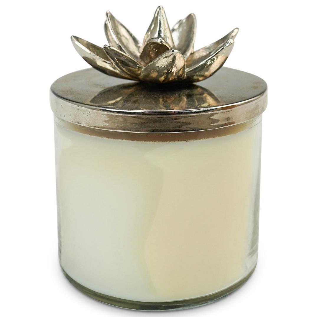 Michael Aram Lotus Blossom Candle: DESCRIPTION: A Michael Aram Lotus Blossom Candle. 13.5 oz. 382 grs. Glass container with metal lid in the carving shape of a lotus flower. Signed on the interior "Aram". CIRCA: 21st Century. ORIGIN: U