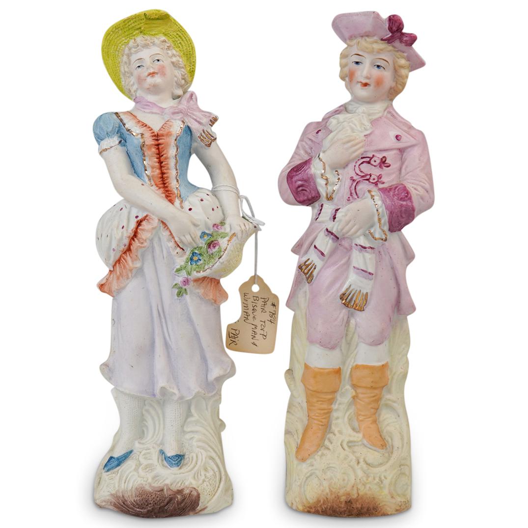 (2 Pc) Antique Dutch Bisque Porcelain Couple Figurines: DESCRIPTION: (2 Pc) Antique pair of hand painted dutch bisque porcelain figurines. Features a young female lady wearing a green hat and lovely colorful dress in pink and blue colors and holding a bask
