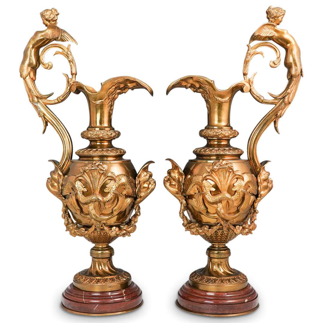 Victor Paillard Dore Bronze and Rouge Marble Ewers: DESCRIPTION: A Pair of French Victor Paillard dore bronze figural bronze ewers. Each of baluster form with winged nude female figural scroll handles. The center is decorated with reliefs of stylised d