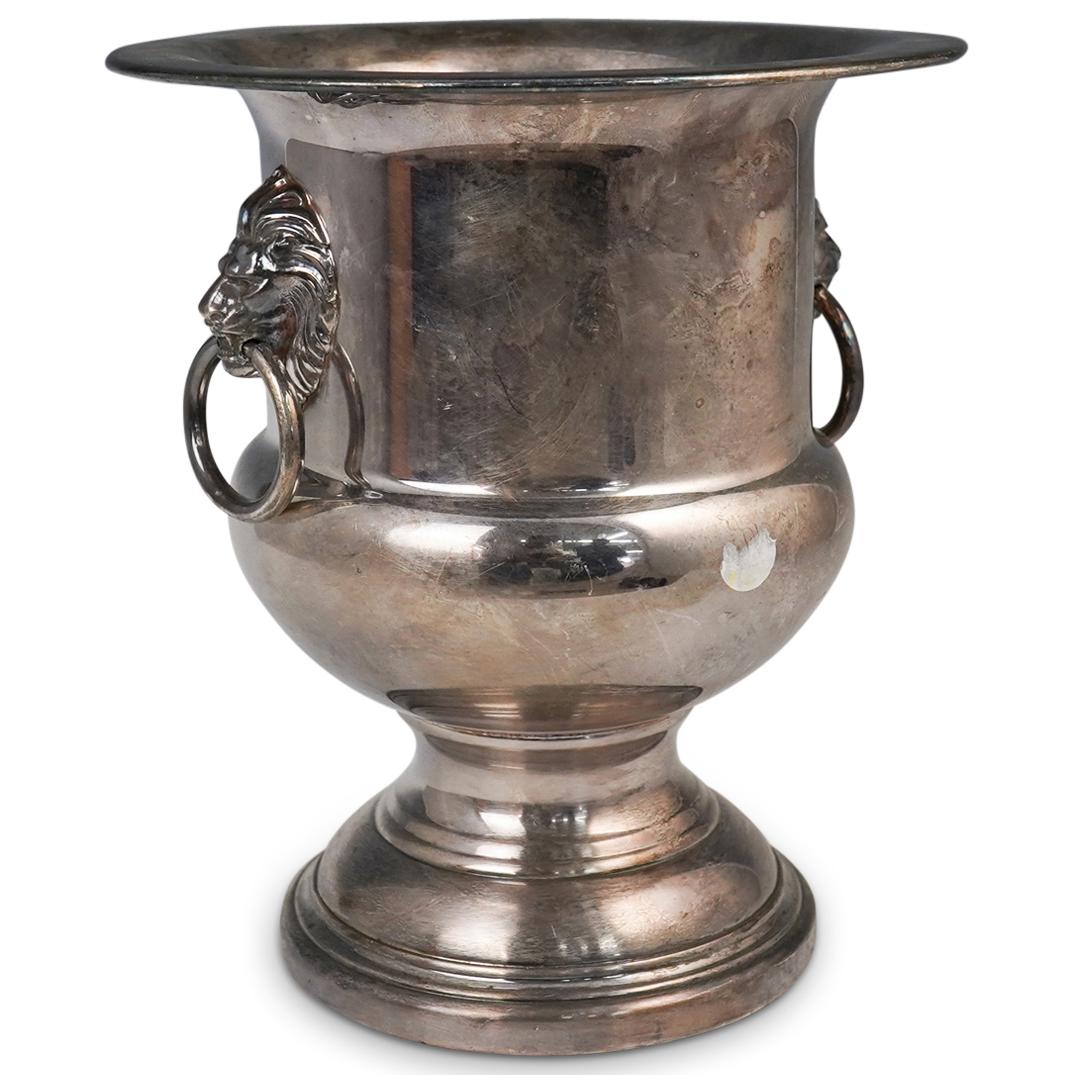 Wallace Silver Plated Lion Head Wine Cooler: DESCRIPTION: A Wallace silver plated wine cooler, flanked on either side with Tete de lion heads holding ring handles, stamped along the underside "Wallace". CIRCA: Early-Mid 20th Cent. ORIGIN: USA DI