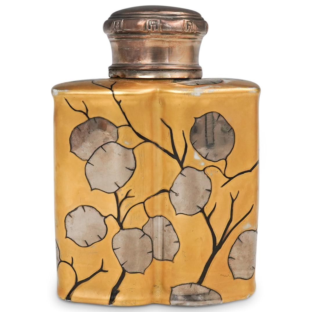 Art Deco Gilt Porcelain Tea Caddy: DESCRIPTION: An Art Deco porcelain tea caddy with gilt and silver fruit adorned branch motifs. Finished with a round decorated silver top. Stamped with red hallmarking underneath. CIRCA: Early - Mid 2