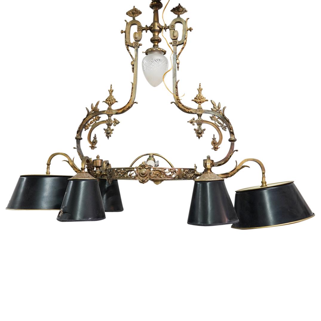 French Bronze & Tin Shade Chandelier: DESCRIPTION: A French bronze chandelier with (3) bulb center sockets flanked by (6) bulb sockets with round black tin mounted shades. Finished with ornate acanthus leaf details throughout. CIRCA: 20th