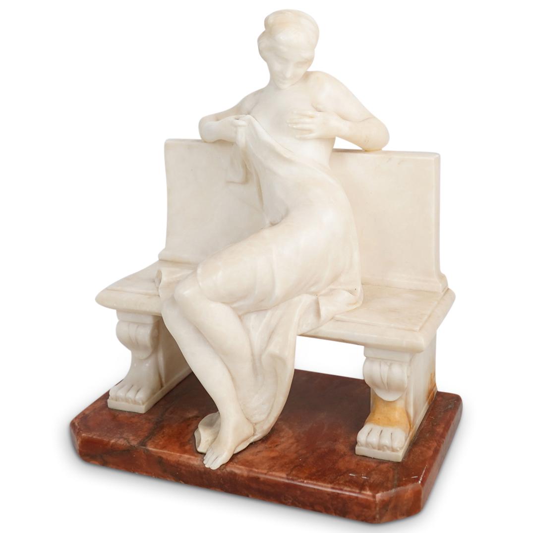 Alabaster "Bazar Colon Montevideo" Sculpture: DESCRIPTION: An alabaster carved figural sculpture featuring a seated semi-nude woman on a Neoclassical style bench with lions paw feet. Artist incised signature and impressed "Bazar Colon Montevideo"