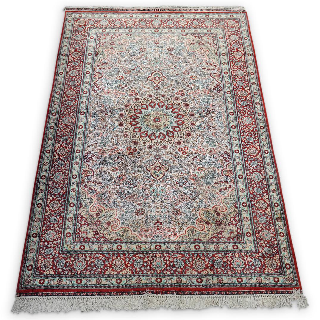 Antique Persian Silk Rug: DESCRIPTION: An Antique Persian silk rug features in a red and beige base color, decorated at the center with multicolored floral decorations and wreaths. Further encompassed by floral borders, comple