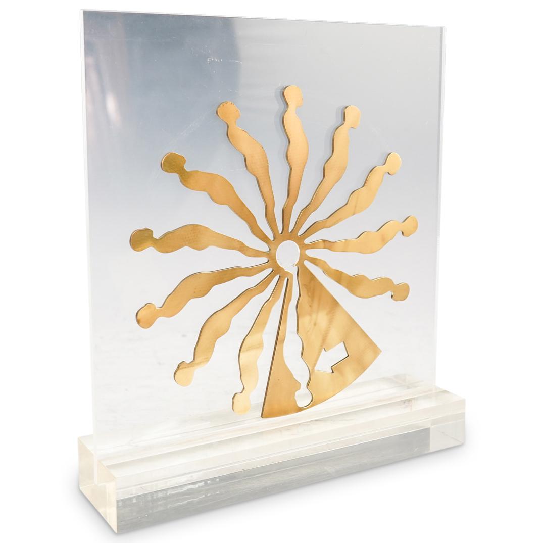 Ernest Trova (American, 1927-2009) "Suspended Relief": DESCRIPTION: A sculpture by surrealist artist Ernest Trova composed of a plexiglass stand and polished brass figural dial, editioned of " 14/175" and stamped with Trova mark. Comes with artists book.