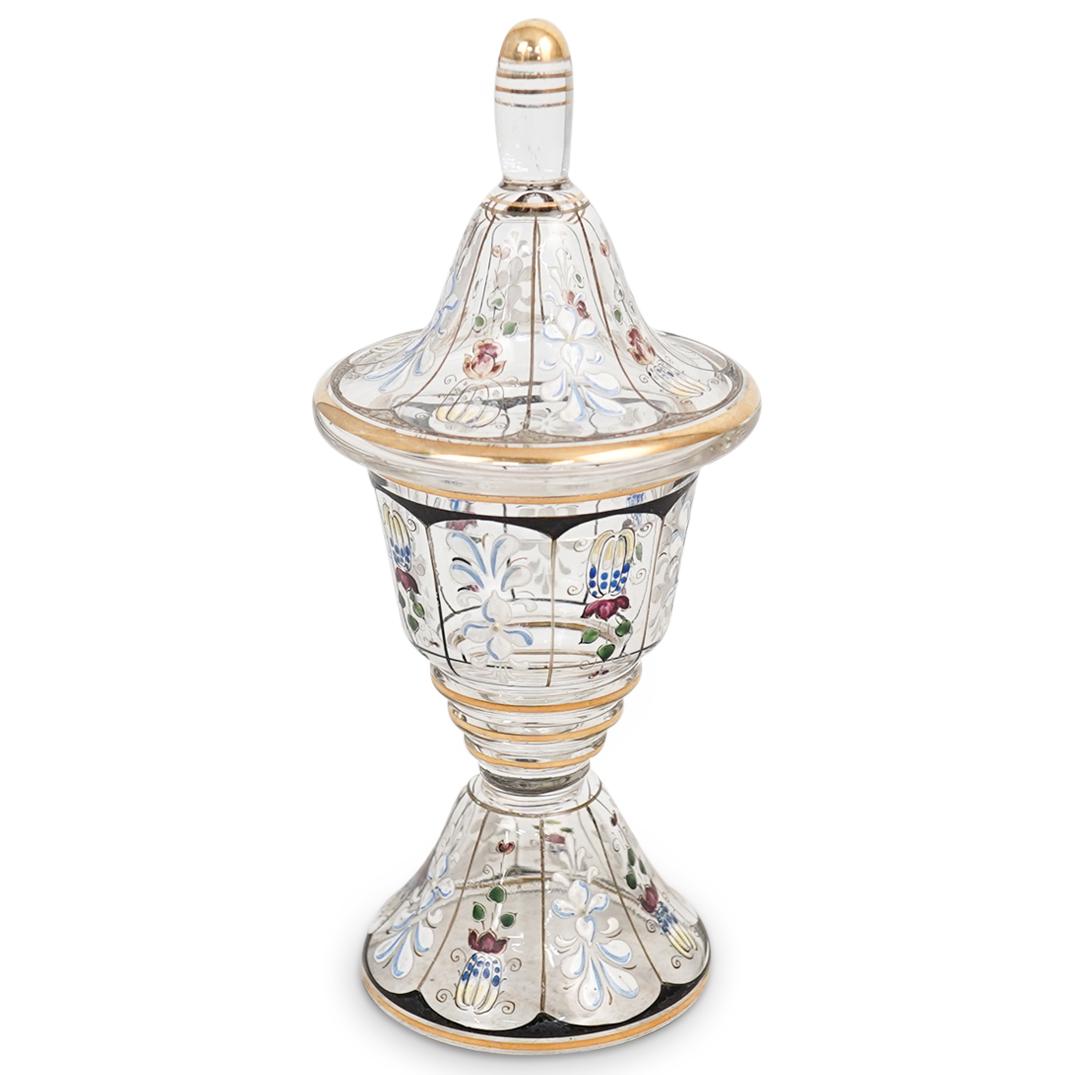 Moser Enamel and Glass Urn: DESCRIPTION: A moser glass urn decorated along the body with multicolored enamel decorations depicting flowers, further accented with gilt trim and bordering. CIRCA: 20th Cent. ORIGIN: Czech DIMENSION