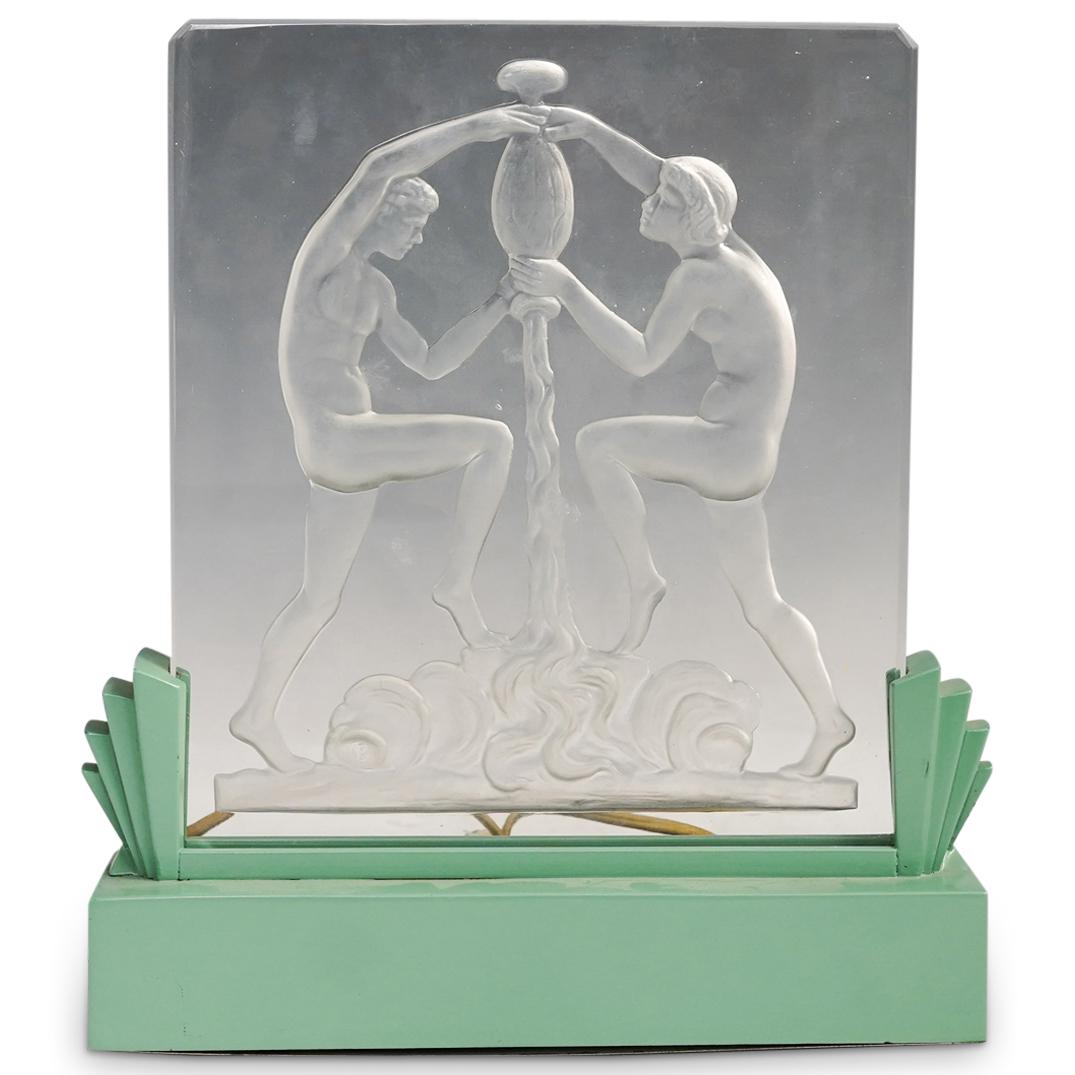 Steuben Glass Figural Relief Luminor: DESCRIPTION: A glass figural relief depicting a classical nude scene (water bearers) green metal luminor base (likely a Crest fixture) Cast lead glass in metal base. Reference: Shape #8461 p. 208. Des