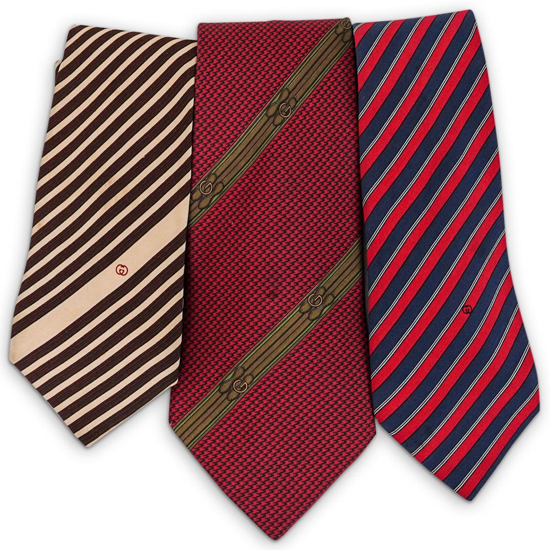 (3Pc) Gucci Silk Necktie Grouping: DESCRIPTION: (3Pc) A grouping of (3) Gucci silk neckties. Includes: (1) Gucci navy and red striped tie. (L: 60" x W: 3.5") (1) Gucci brown and beige striped tie. (L: 60" x W: 3.5") (1) Gucci red silk