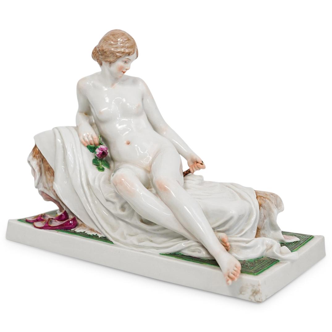 Meissen Female Reclining Nude Porcelain: DESCRIPTION: An antique Meissen porcelain figurine Model T 185 by Robert Ockelmann. The figurine depicts a female nude reclining on a chaise longue. A pair of magenta slippers is laid next to the chai