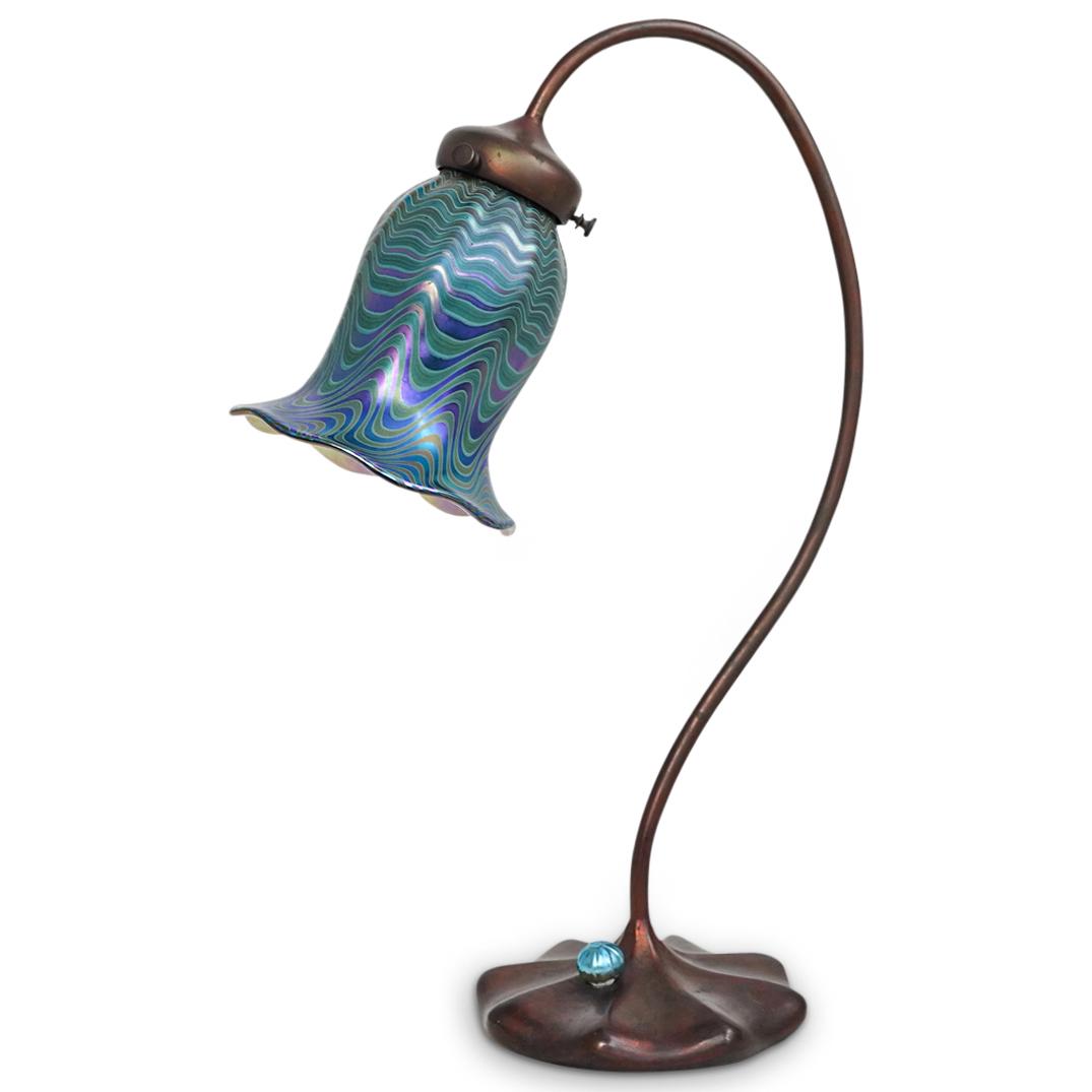 John Cook Studios Table Lamp: DESCRIPTION: A John Cook signed art glass table lamp with bronze Tiffany style base. Finished with an iridescent blue scalloped glass shade. Signed underneath: "John Cook Studios" CIRCA: 20th Century.