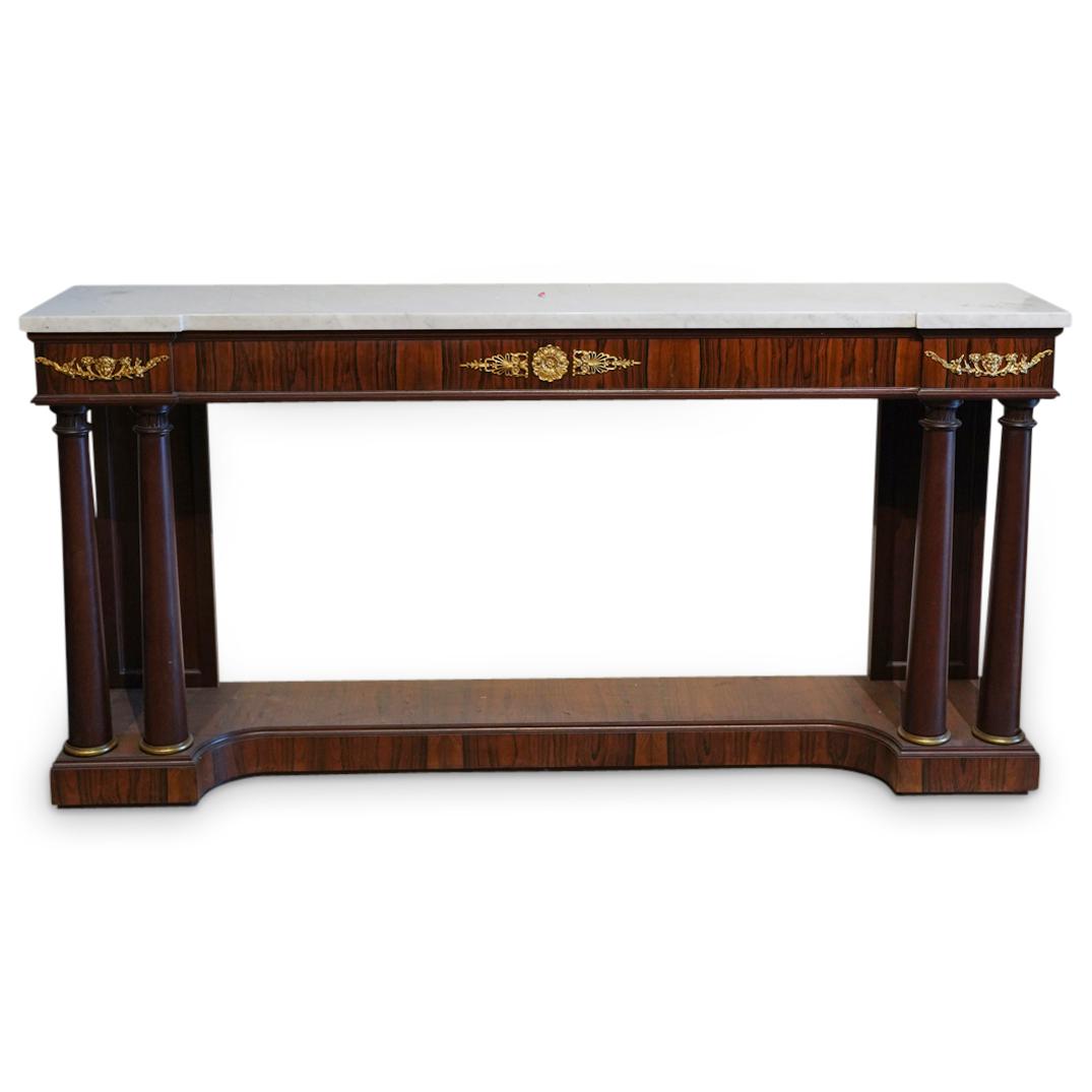 Empire Style Mahogany & Ormolu Console: DESCRIPTION: An Empire style mahogany and ormolu console designed with an elongated shape with rich ormolu decorations and crafted with a white marble top and two column supports flanking each frontal