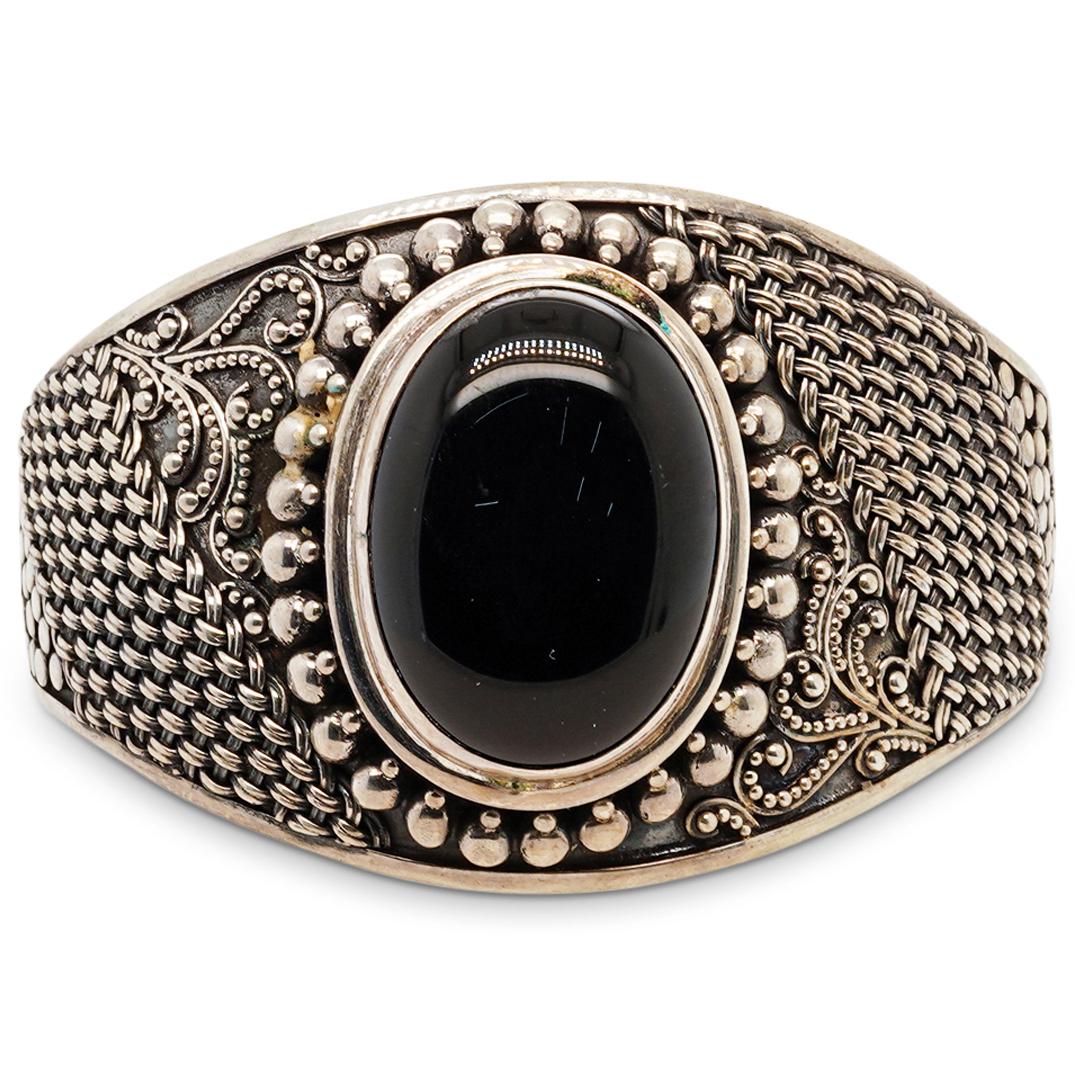 Sterling Silver and Onyx Cuff: DESCRIPTION: A sterling silver cuff decorated along the band with beaded designs and filigree patterns, centered by an Onyx Cabochon. Stamped along the under band "925 Indonesia". Total Weight: 80 Gra