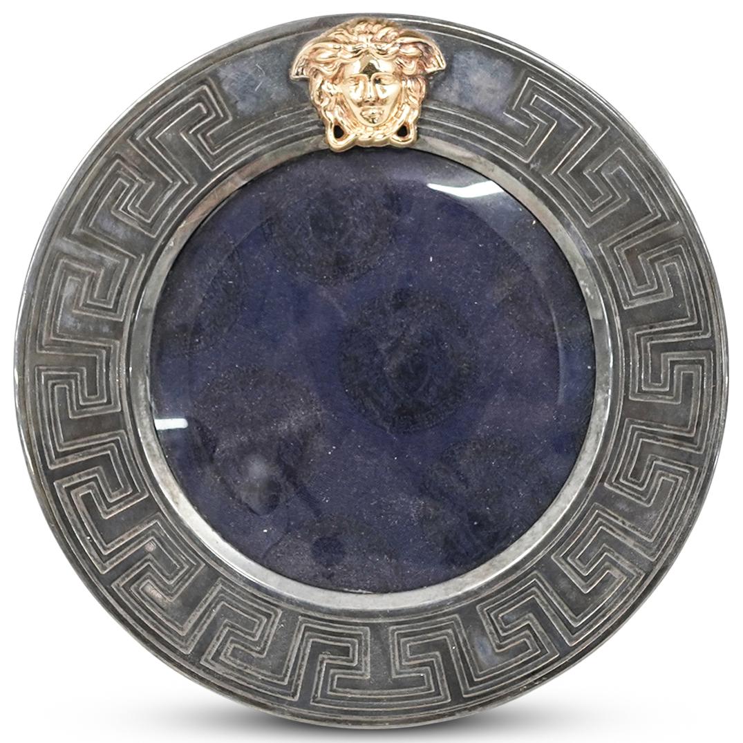 Versace Medusa Circular Photo Frame: DESCRIPTION: A Versace Medusa photo frame in a circular shape with carved decorative motif and gold colored Medusa head on top. CIRCA: 20th Century. ORIGIN: Italy. DIMENSIONS: W: 8". Have a similar it