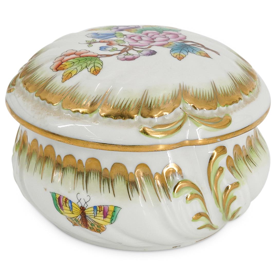 Herend Queen Victoria Porcelain Lidded Jar: DESCRIPTION: Lidded jar with white ground color and floral motif finished with gilded trim. Stamped "Herend-Hungary". CIRCA: 20th Century. ORIGIN: Hungary DIMENSIONS: W: 4.75" H: 3". Have a similar it