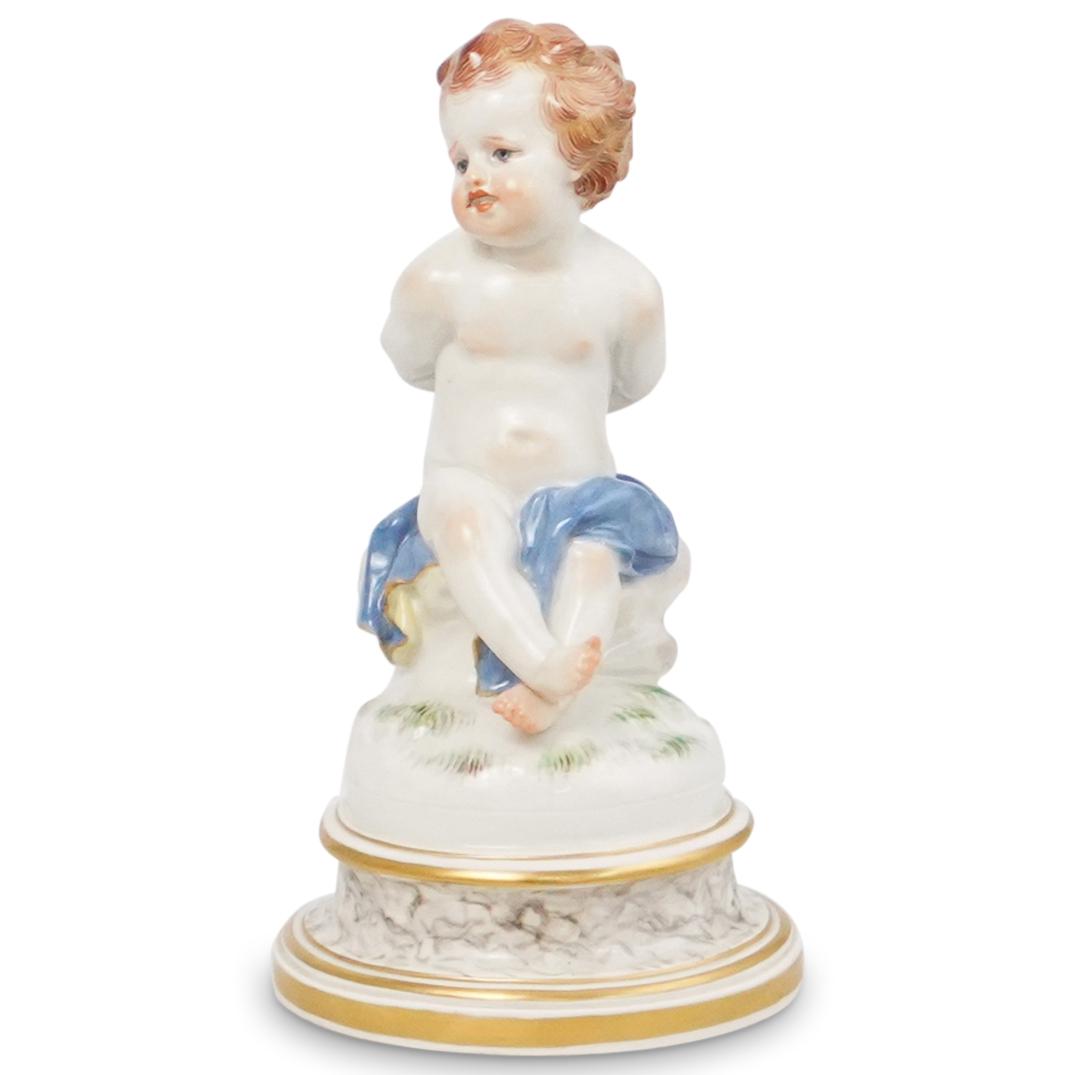 Meissen Porcelain "Putti" Figure: DESCRIPTION: A Meissen porcelain "Putti" figure. Features a hand painted cherub "Putti" figure with hands tied in ribbon. Mounted to round gilt accented base. Marked underneath with underglaze blue "M