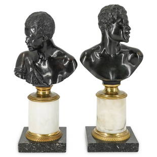 Antique Bronze Blackamoor Busts On Marble Stands: DESCRIPTION: Pair of bronze busts, one of a Nubian man and one of a Nubian woman. Each bust is attached to the gilded cap of a white marble stem which rests in a gilded ring on a black marble base.