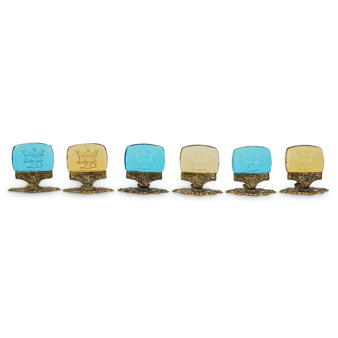 (6 Pc) Ornate Ormolu & Glass Card Holders Set: DESCRIPTION: (2 Pc) A set of six ornate ormolu & colored glass card holder set, in amber and blue colored glass with an engraved decoration depicting playing children. CIRCA: 20th Century. DIMENSIONS: