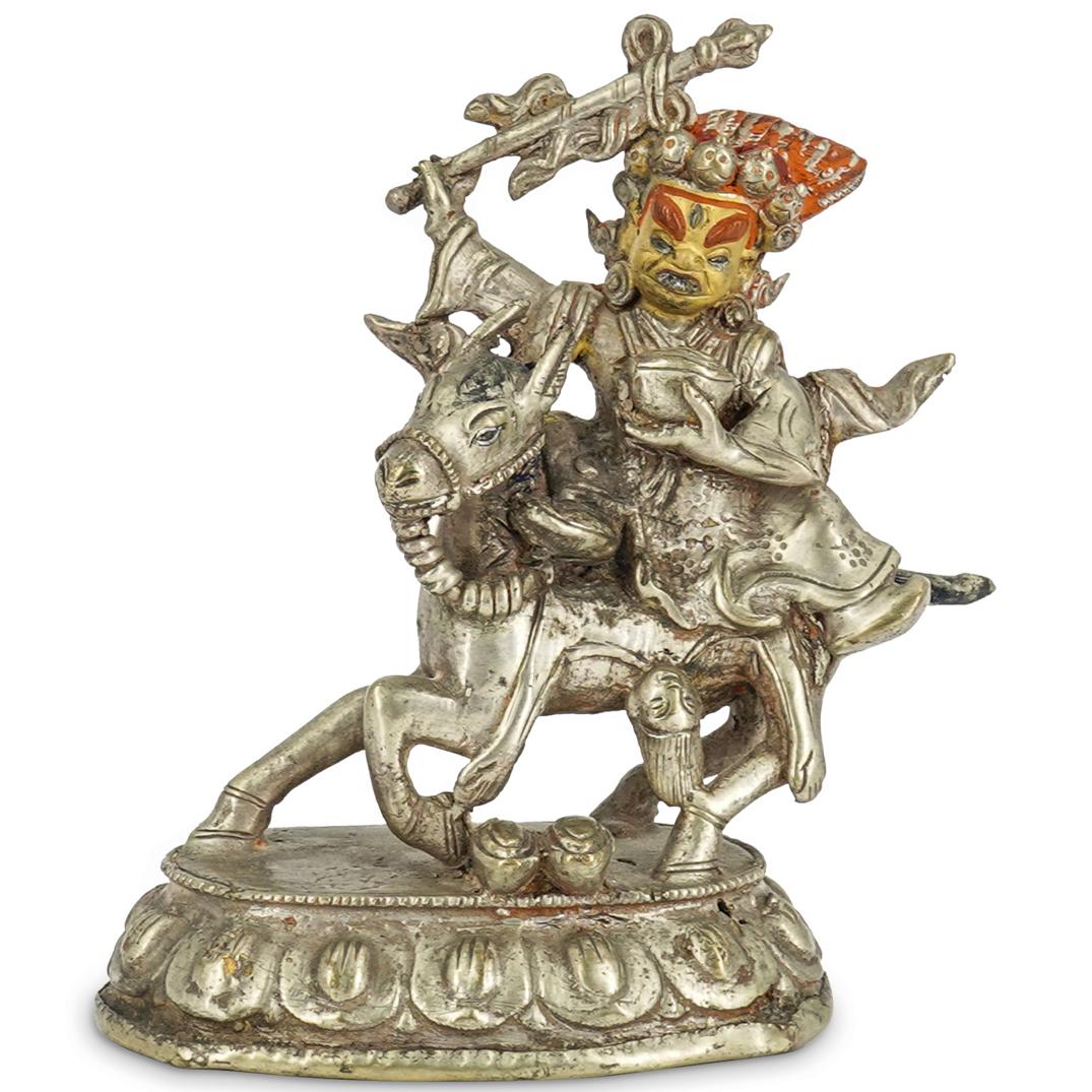 Early Silver Figure Of Mahakala: DESCRIPTION: Early silver figurine of Mahakala in his black-cloaked form riding a donkey and holding a mace in his right hand and a bowl in his left; a woman is splayed beneath him on the donkey. Maha