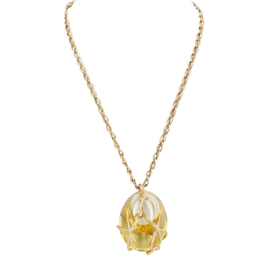 Lalique Necklace W/ Light Yellow Crystal Nugget Pendant: DESCRIPTION: A Lalique necklace designed with a large oval nugget ring-shaped pendant. The pendant is crafted in clear to light yellow colored crystal with an overlay of gold metal decorations. The go
