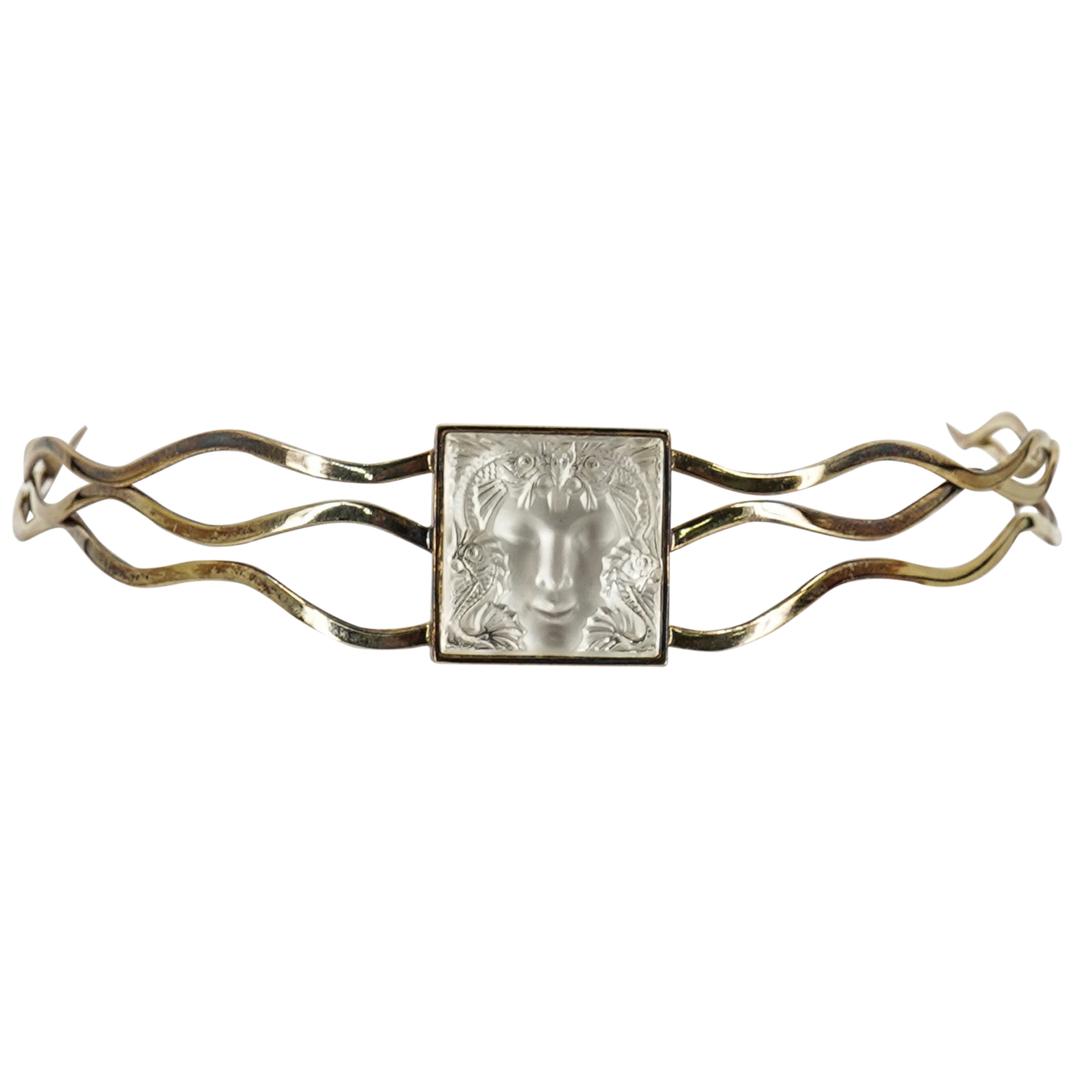 Lalique "The Masque de Femme" Choker Necklace: DESCRIPTION: A Lalique "The Masque de Femme" choker necklace. The choker frame is designed in gold-colored metal with an intricate wavy pattern. The central motif displays a "Masque de Femme" carved c