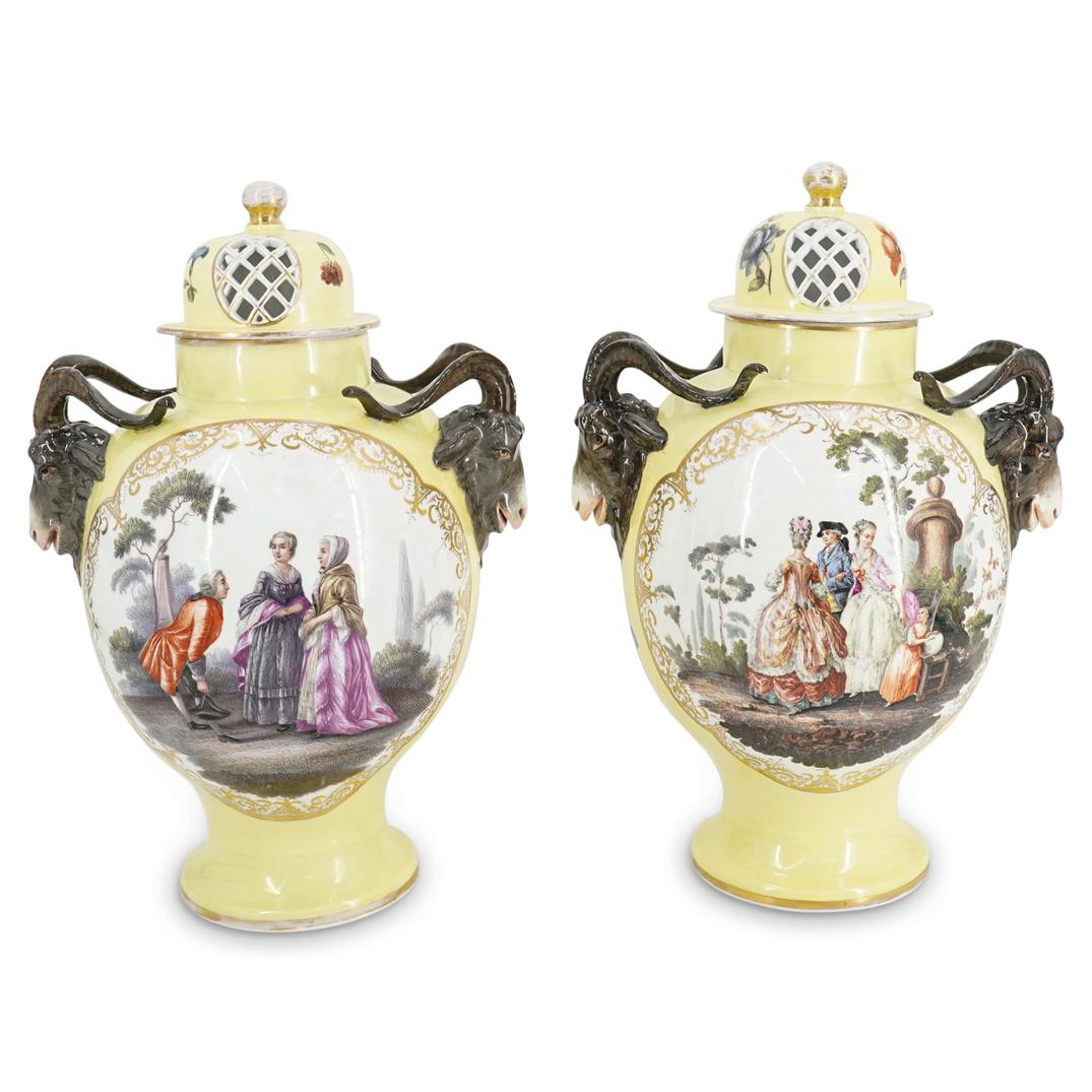 Pair of Meissen Porcelain Lidded Urns: DESCRIPTION: Pair of Meissen glazed porcelain urns featuring enamel depictions of flowers and figures in a garden over lemon ground. Gilt details throughout, open work weaved lid, and high relief goat
