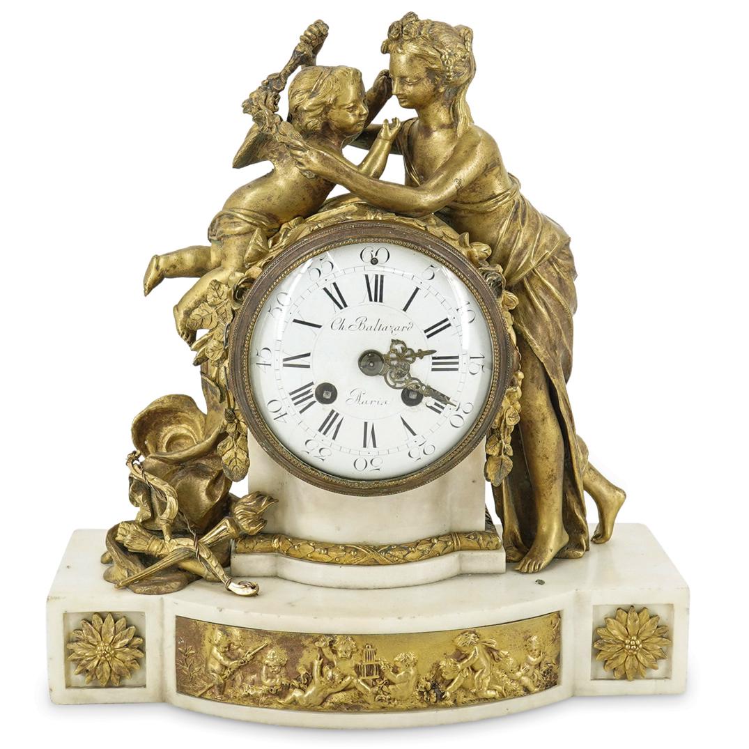 French G. Schmoll Bronze And Marble Figural Clock: DESCRIPTION: Mantel clock featuring a bronze and marble casing decorated with a figure of a woman wrapping a garland around a winged putto. Piece is further embellished with floral, foliage, garland,