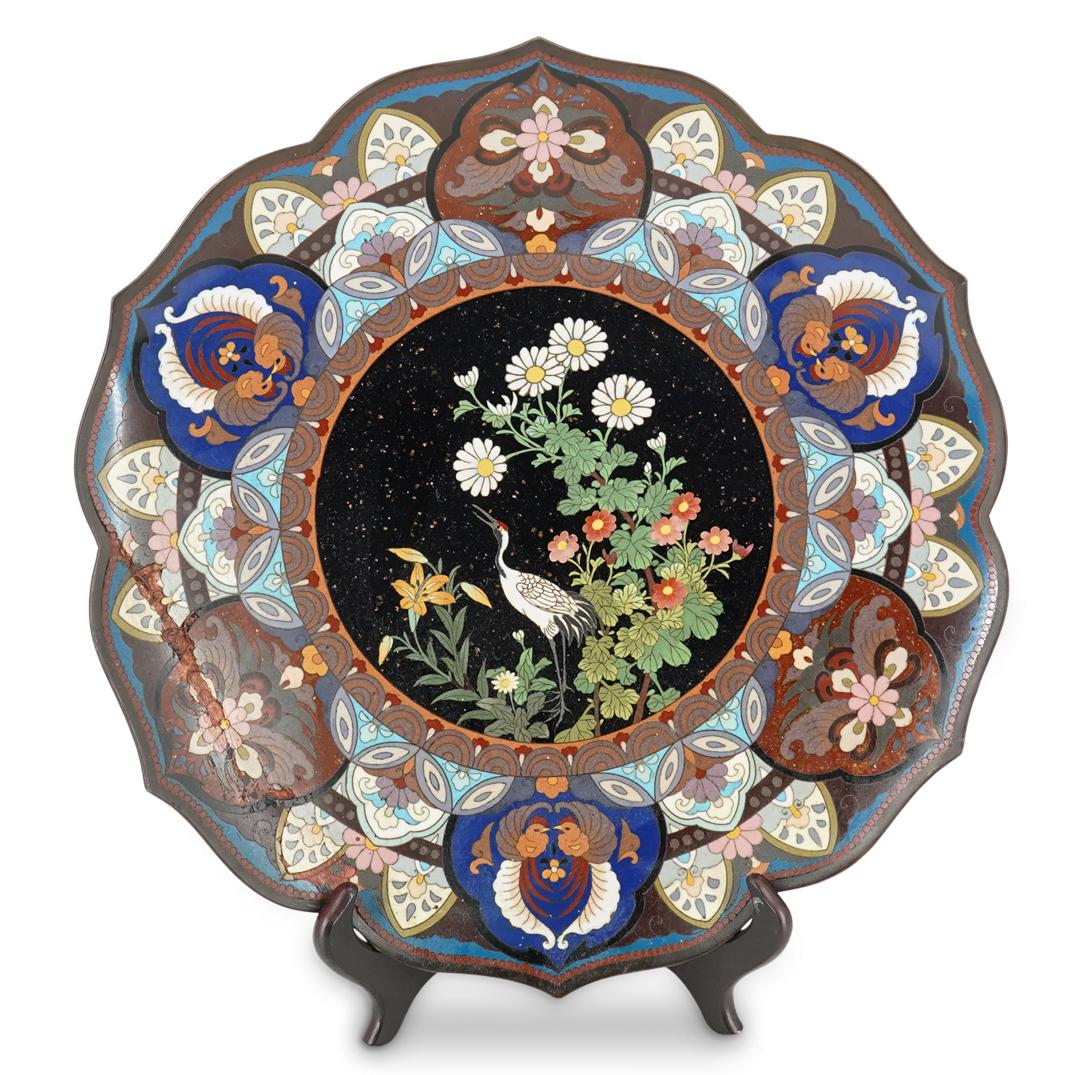 Japanese Cloisonne Charger: DESCRIPTION: Cloisonne charger featuring a central image of a crane among flowering foliage against a black background decorated with aventurescent flecks. Central image is surrounded by floral and fo