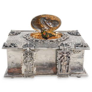 Attributed To Karl Griesbaum Silver Book-Form Singing Bird Box: DESCRIPTION: Karl Griesbaum attributed German book-form singing bird box, features a silver foundation with ornate engraved foliate decoration throughout, finished with figural pierced strap and