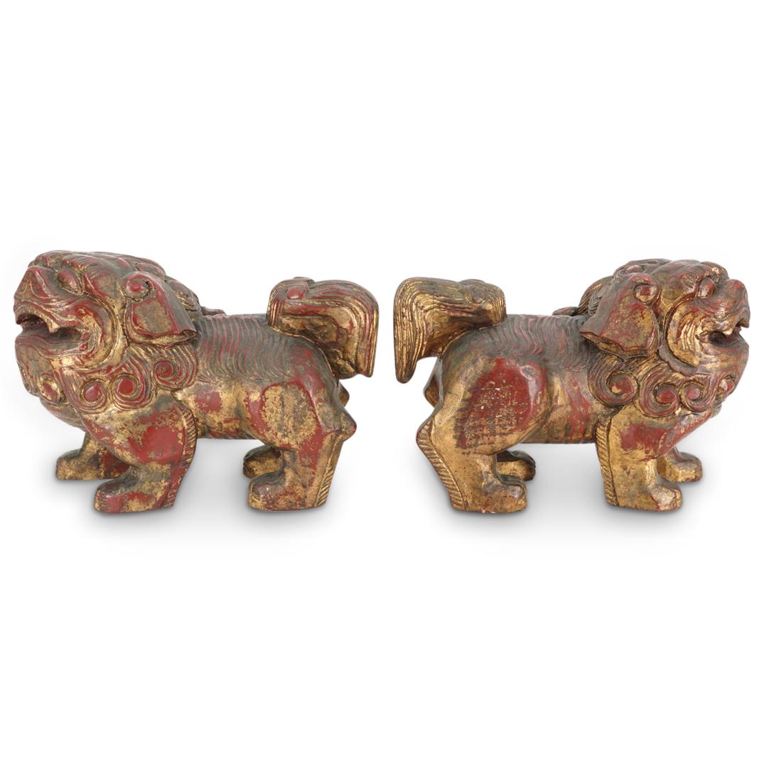 (2 Pc) Chinese Wooden Guardian Lions: DESCRIPTION: Pair of matching wooden guardian lions ("foo dogs"), each of which features a red patina embellished with gold accents. One faces its left, the other faces its right. CIRCA: 20th Century