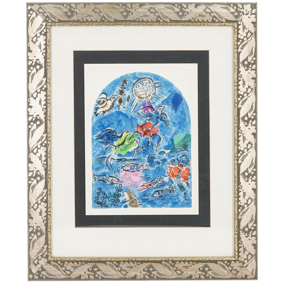 Marc Chagall "Tribes of Reuben Window" Lithograph: DESCRIPTION: Lithograph of Marc Chagall's painting "Tribes of Reuben". Depicting birds, sea and fish beneath orb with Hebrew. Mounted in raised silver toned foliage frame with white matting. CIRCA: 20