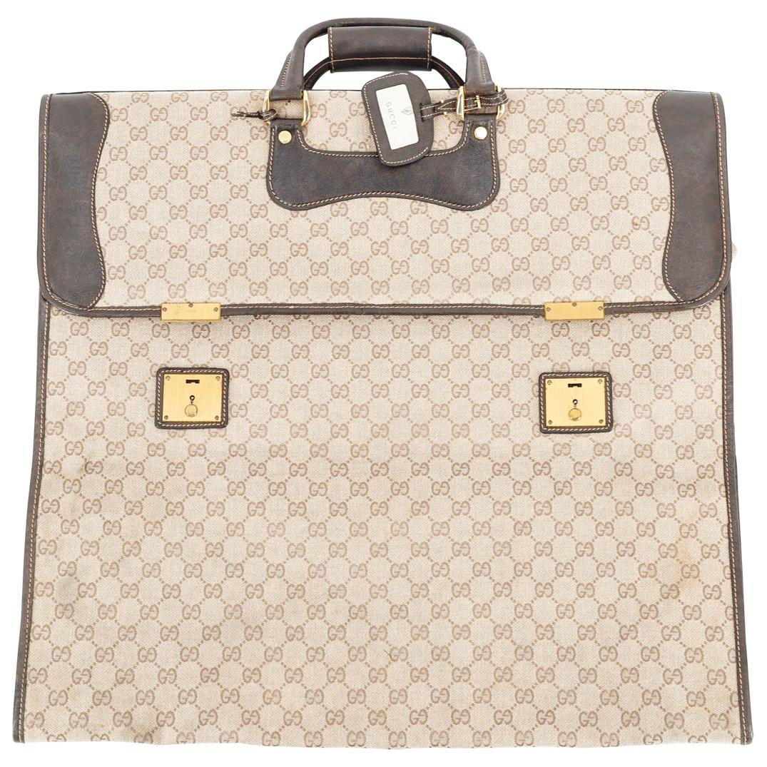 Gucci Beige Garment Bag: DESCRIPTION: Gucci beige folding garment bag with brown leather, zipper, and gold toned key latches. Leather tag inside embossed "Made in Italy by Gucci" and stamped in other places throughout. CIRCA: