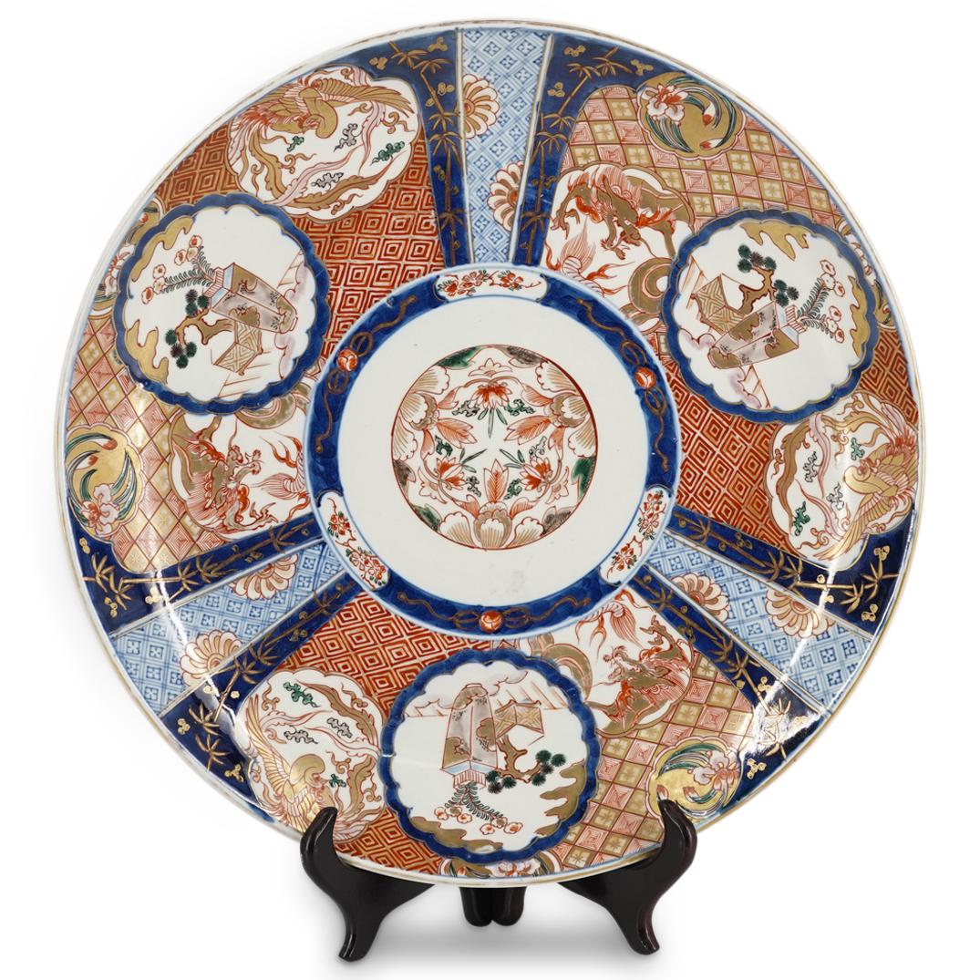 Antique Chinese Imari Porcelain Charger: DESCRIPTION: Imari porcelain charger decorated with a central image of floral motifs and images on the lip of a flower vase next to a potted bonsai. Images on lip are surrounded by lattice patterns an