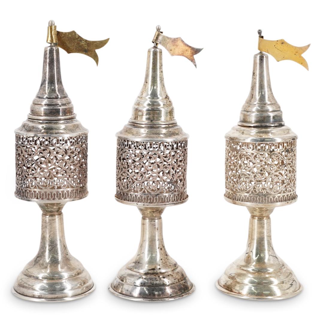 (3 Pc) Judaica Sterling Silver Besamim Spice Towers: DESCRIPTION: Three footed sterling silver besamim spice towers, each featuring a reticulated body decorated with foliage designs and crowned with a cap finished with a banner. Each piece is marked "ST