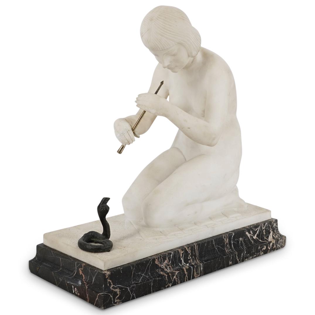After Guglielmo Pugi Nude Snake Charmer Marble Sculpture: DESCRIPTION: After Guglielmo Pugi, an Art Nouveau marble sculpture of a nude woman kneeling while holding a bronze horn directed at a coiled up bronze cobra sculpture. Signed at the left side "Pugi".