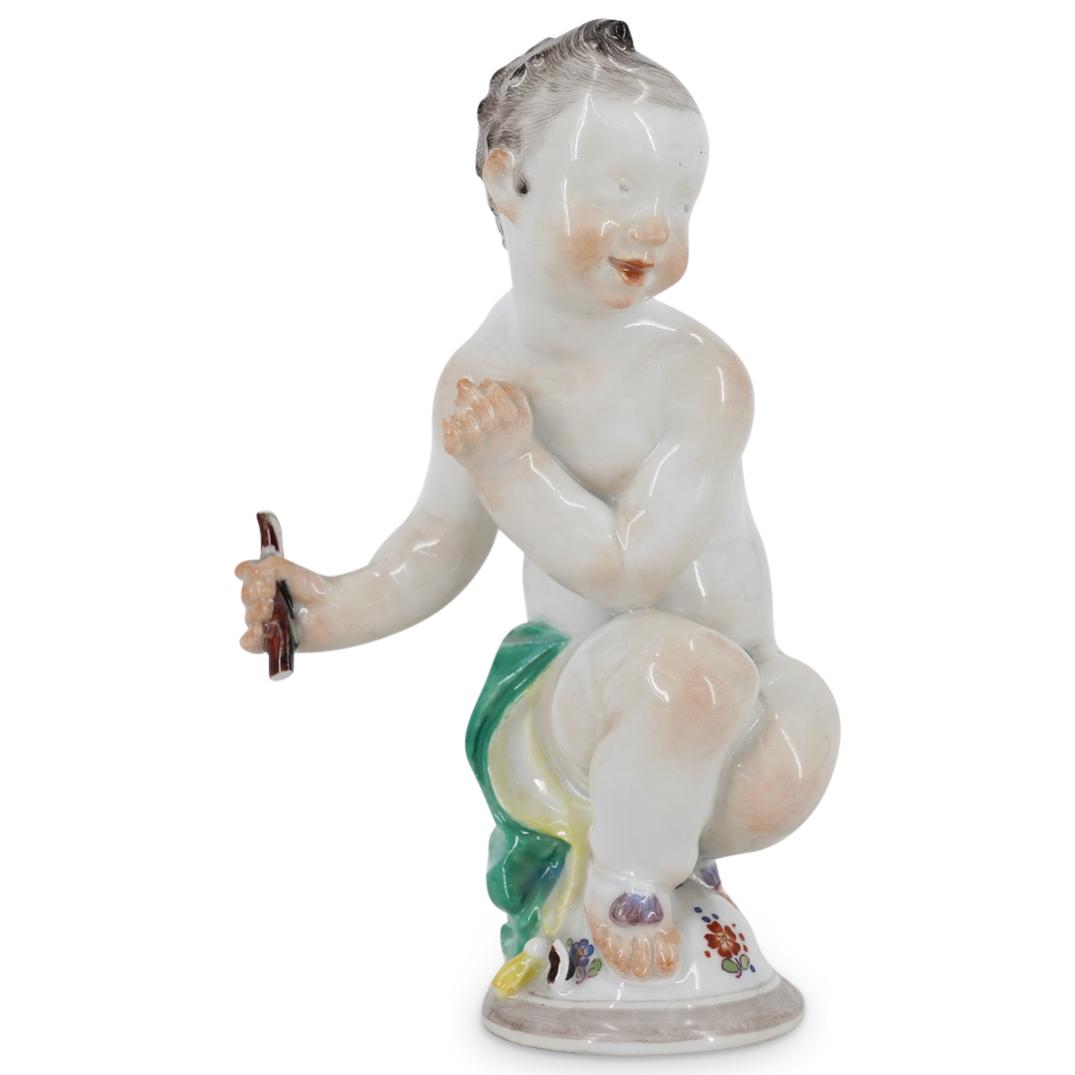 Antique Meissen Porcelain Figurine: DESCRIPTION: Antique Meissen glazed porcelain sculpture of a figure squatted and holding a stick with rosy toned details at the cheeks, nose, shoulders, knees and feet; As well as a green robe and oth