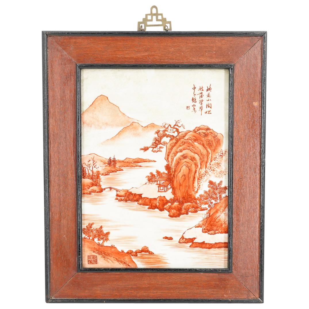 Framed Chinese Riverside Landscape Painting On Porcelain: DESCRIPTION: Framed landscape painting in red ink on porcelain depicting a riverside landscape punctuated by one building and a bridge. Marked at top right in Han characters and at lower left in seal 