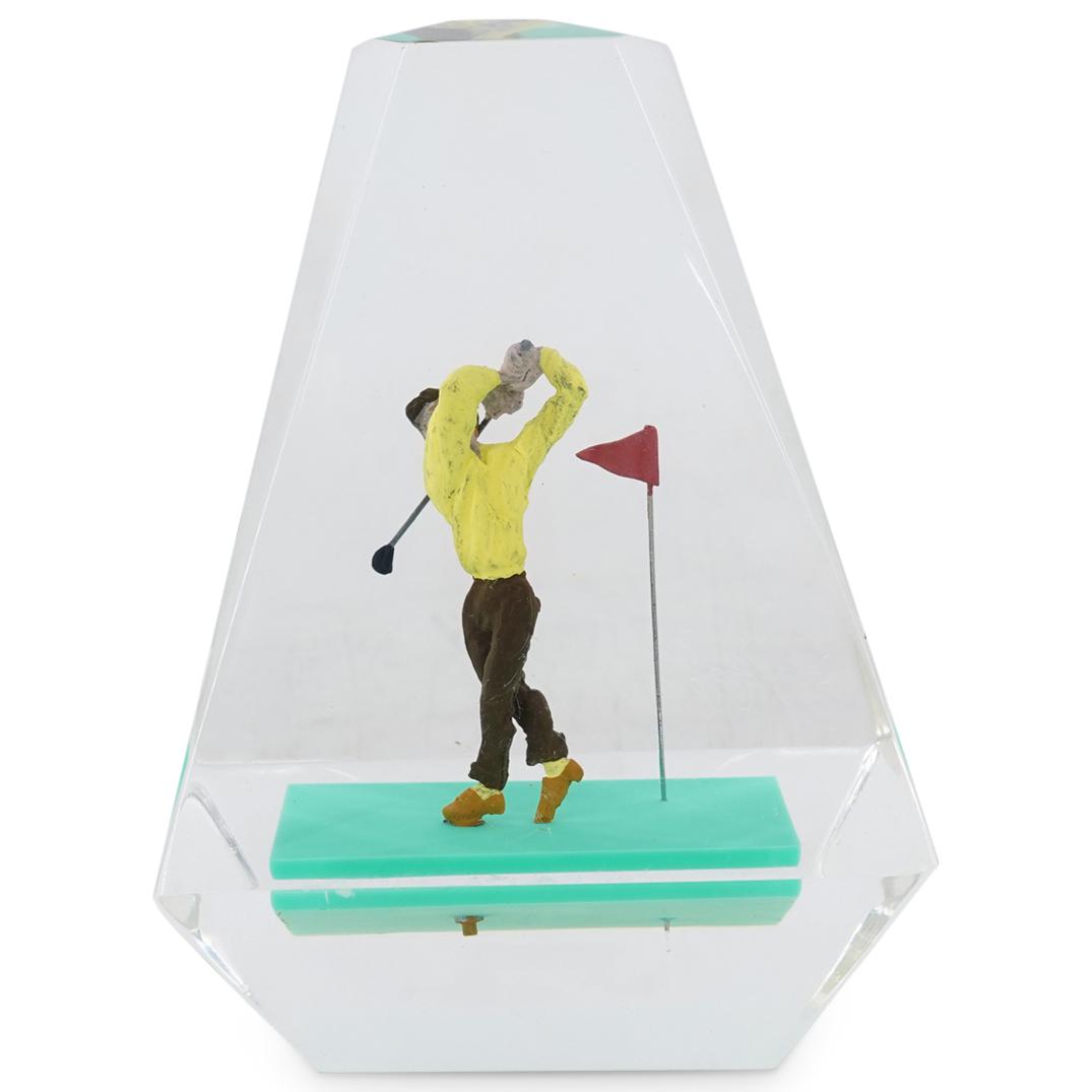 Sports-Theme Golf Lucite Sculpture: DESCRIPTION: A Sports-themed lucite sculpture depicting a clear acrylic pyramidal block with an interior male figure playing golf. CIRCA: 20th Century. DIMENSIONS: H: 6 1/2" W: 4 1/2" D: 4". Have a si