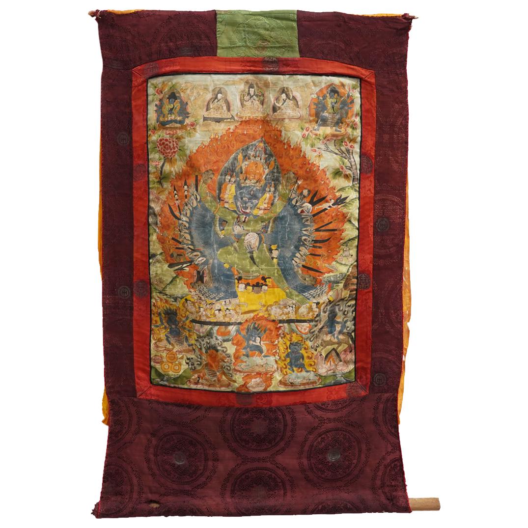 Antique Tibetan Vajrabhairava Thangka: DESCRIPTION: Thangka depicting Vajrabhairava wearing a wrathful deities crown, clutching a variety of weaponry in his numerous hands, and standing in the left-leg-straightened posture as he mates with