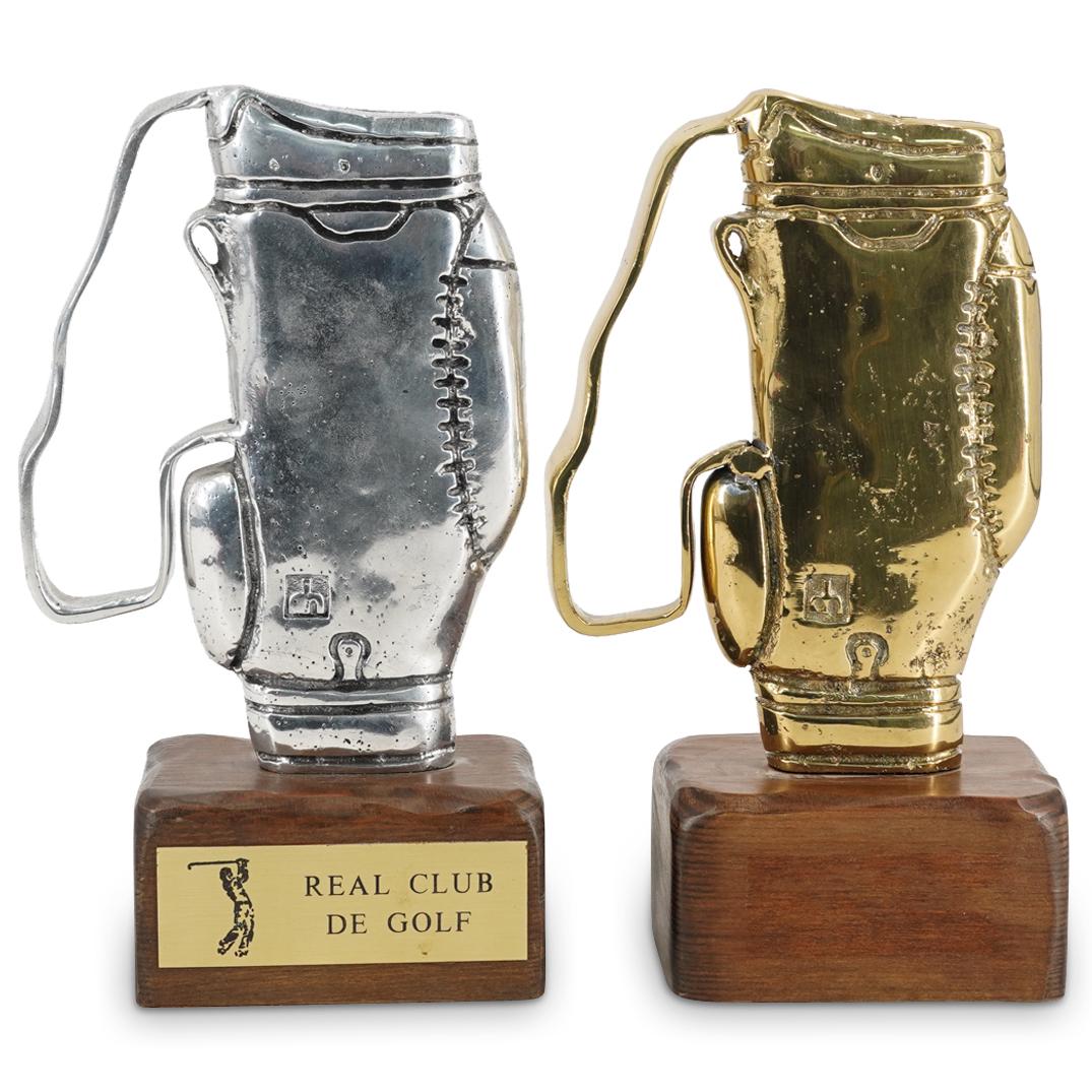 (2Pc) David Marshall Golf Trophies: DESCRIPTION: (2Pc) David Marshall designer golf trophies composed of one aluminum trophy, and one brass trophy. Each fitted to wooden bases. The aluminum bag is plaqued: "Real Club De Golf" marked wit