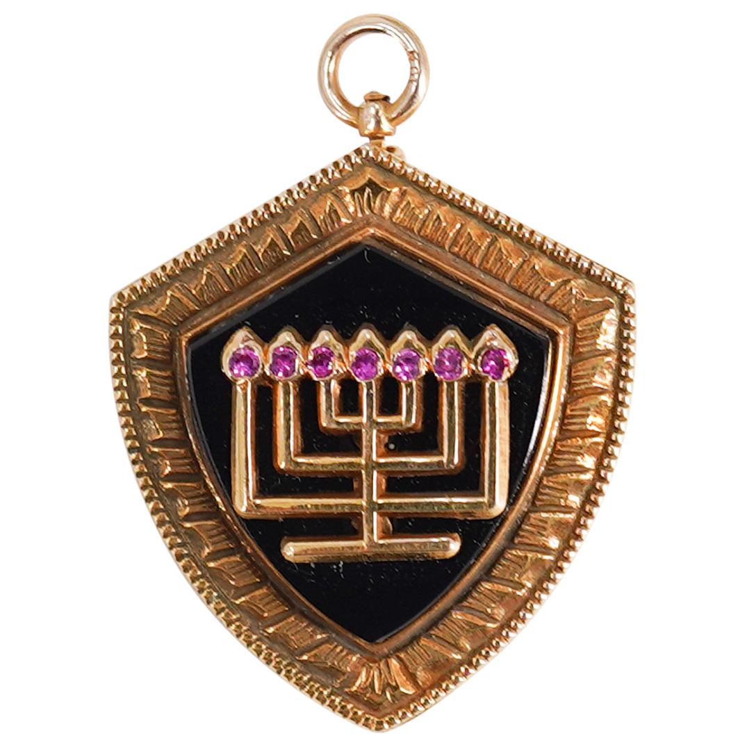 14k Gold and Onyx Menorah Pendant: DESCRIPTION: A 14k gold pendant features a gold foundation fitted at the center with Black onyx inert overlaid with a Menorah motif, set with a Seribes of Rubies. Stamped along the back "14k". Total W