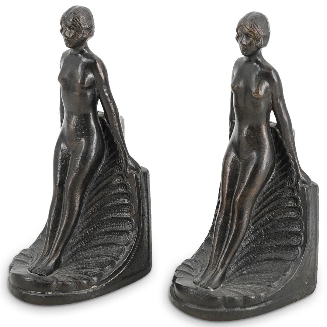 (2Pc) Pair of Art Deco Style Nude Metal Bookends: DESCRIPTION: (2Pc) Pair of art deco style lacquered metal bookends depicting a nude lady standing on a seashell. Felt lining at the underside embossed "Design Toscano". CIRCA: 21st Century ORIGIN: USA