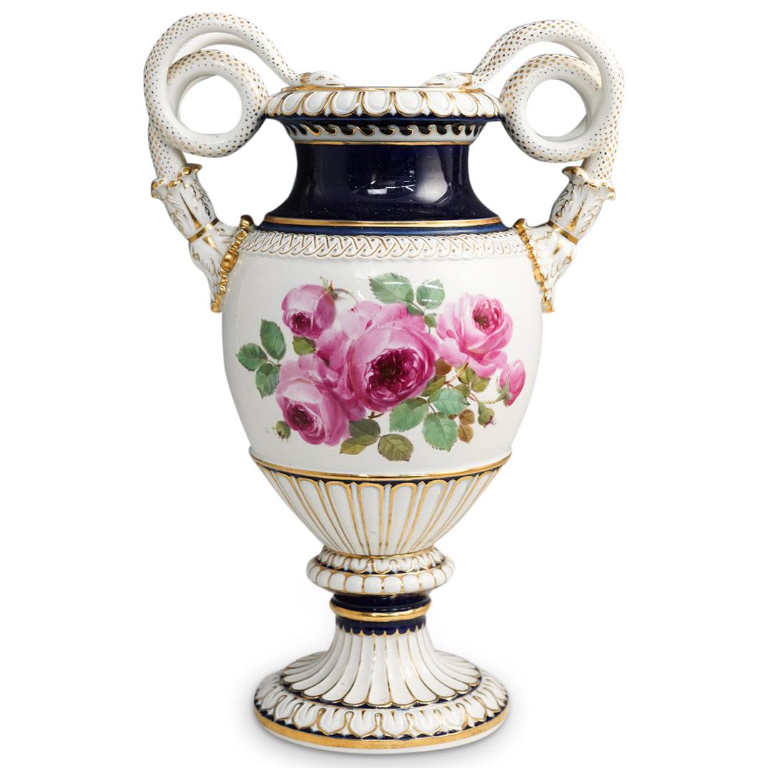 Large Meissen Serpentine Porcelain Urn: DESCRIPTION: A large meissen porcelain urn features floral depictions over a white ground, further decorated with Cobalt blue and gilt accents, completed with coiling serpentine handles. Marked with M
