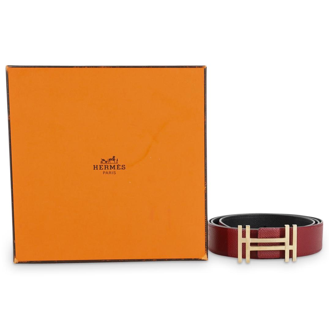 Hermes Au Carre Permabrass Belt in Box: DESCRIPTION: Hermes black and red leather belt with permabrass Au Carre buckle presenting a pierced double "H" design. Includes original box and dust bag. Etched at the backside of the buckle "Made in