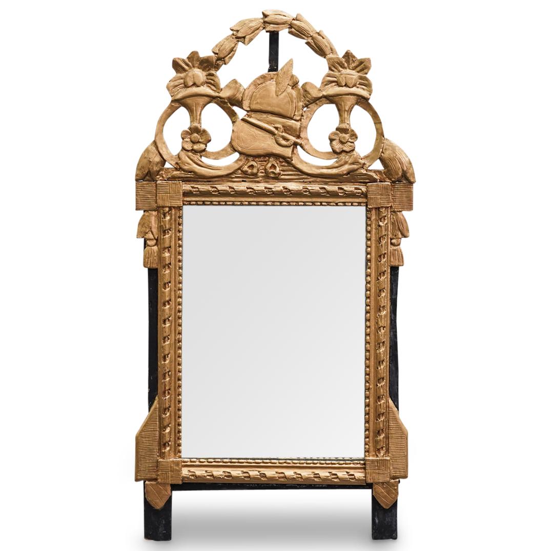 Antique French Giltwood Mirror: DESCRIPTION: An antique French giltwood and gesso mirror with ornate bordering, and ebonized details. Completed with mounted helmet, novel, and horn crest. CIRCA: 19th Cent. ORIGIN: France DIMENSIONS: