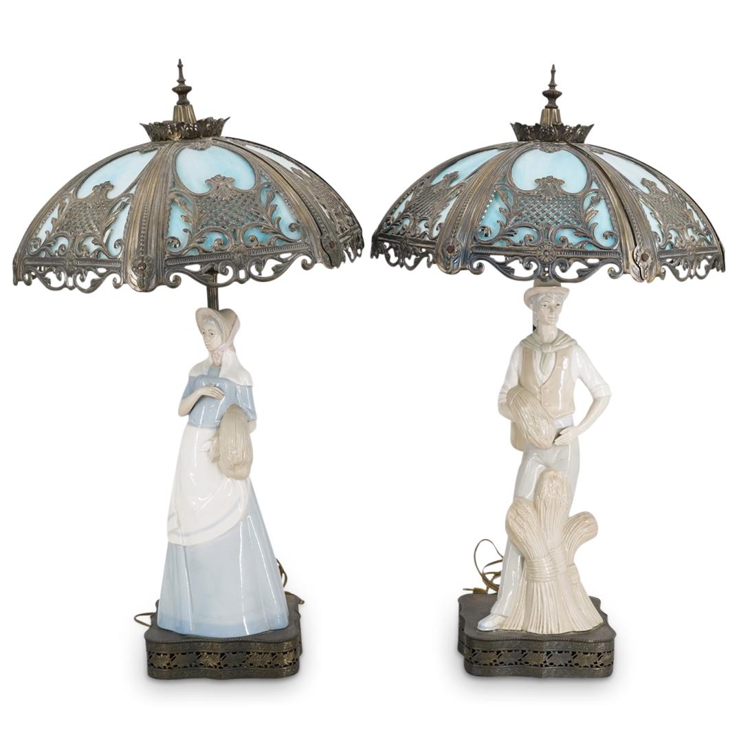 (2Pc) Pair of Lladro style Porcelain & Brass Lamps: DESCRIPTION: (2Pc) Pair of brass lamps featuring Lladro style porcelain sculptures atop the bases of a farmer man and a woman, pierced foliate designs in relief around the base, fluted stems, and open