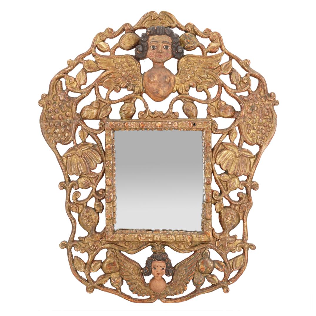 Antique South American Gilt Gesso Carved Wood Mirror: DESCRIPTION: Antique South American gilt gessoed and carved wood frame polychrome painted comprising of pierced foliate scroll designs throughout featuring a nude females torso with spread wings at th