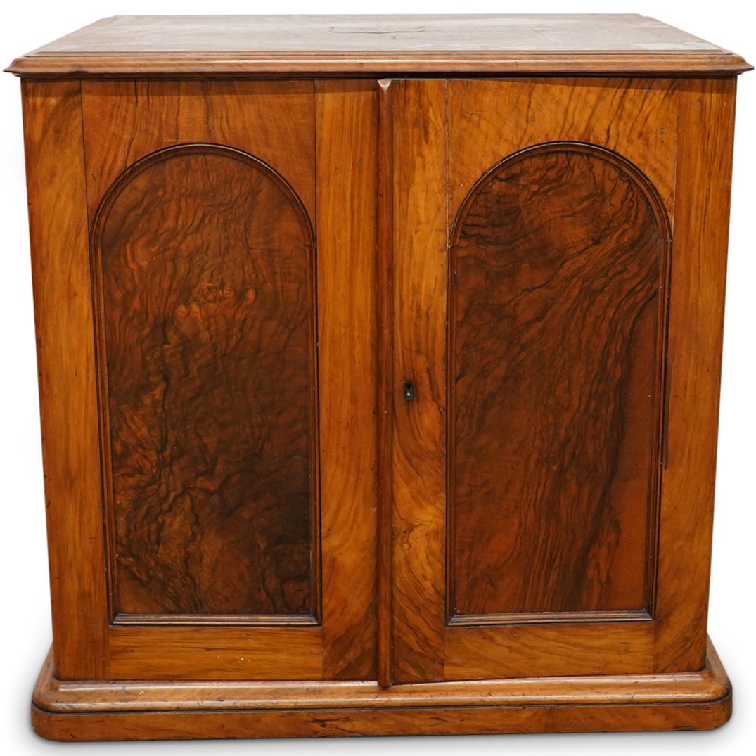 Ollivant & Botsford Edwardian Bookmatch Cabinet: DESCRIPTION: An antique Edwardian bookmatch wood silverware cabinet with burl veneer arched doors, three storage shelves with pull-out top drawer, completed with brass inlay shield at table top and ca