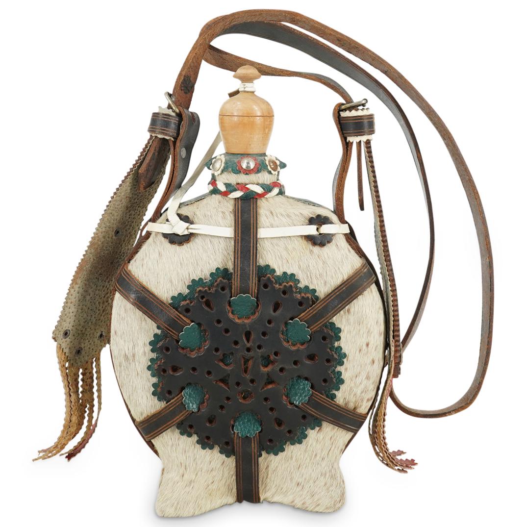 Vintage Hungarian Fur & Leather Flask: DESCRIPTION: Vintage Hungarian flask wrapped with white fur and overlaid with black, green and red leather straps pierced with geometric designs throughout with further details of a wood cap and leath